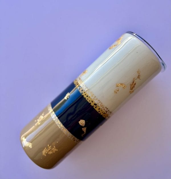 safari style 20 oz skinny tumbler gold leaf with a blue, tan and off white backdrop
